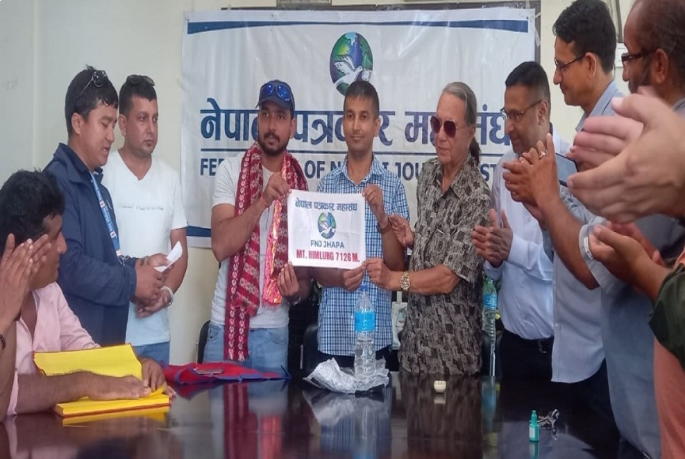 फोटो पत्रकार जोशी पत्रकार महासंघ झापाको झण्डा लिएर हिमाल आरोहणमा